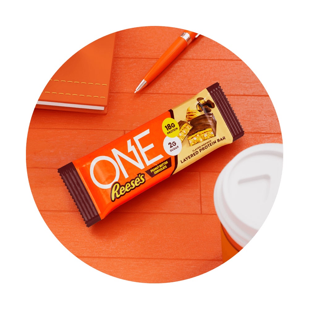one reeses peanut butter chocolate flavored layered protein bar surrounded by school supplies